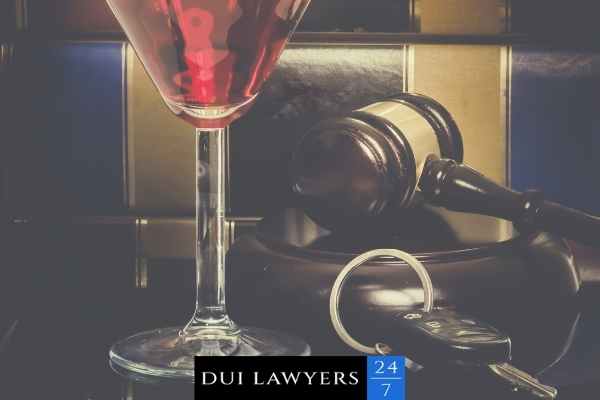 an image of car keys, a gavel, a mixed drink, and legal books on a lawyers desk